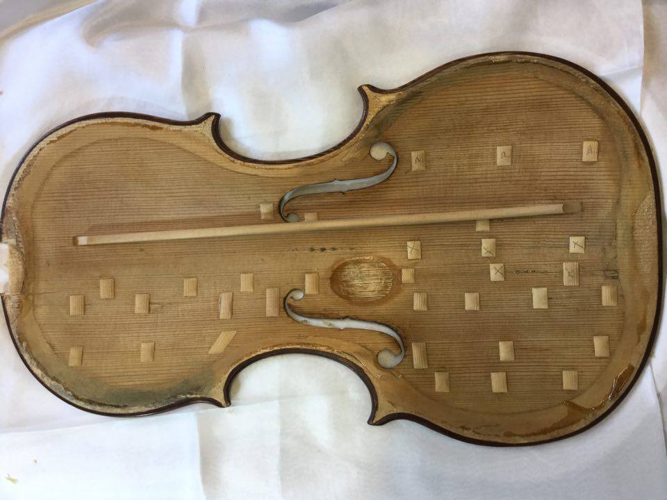 An image of the inside front price of a violin, ready for repair